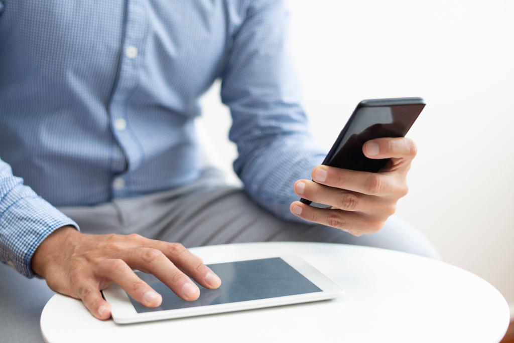 closeup-man-using-smartphone-tablet-coffee-table.jpg